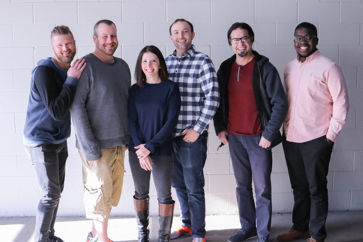 The Jed Mahonis Group team casually standing around and awkwardly posing for a company photo.